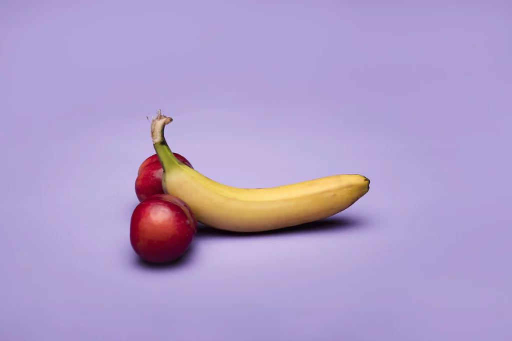 Banane mit Kirschen, die symbolisch den Penis mit den beiden Hoden darstellt