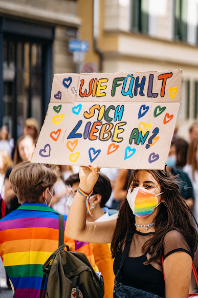 Frau auf queerer Demo mit Schild "Wie fühlt sich Lieb an?"