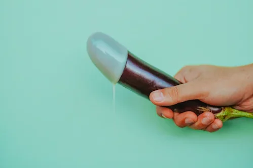 Eine Avocado mit eine Gummiüberzug wird in der Hand gehalten und soll einen Penis symbolisieren